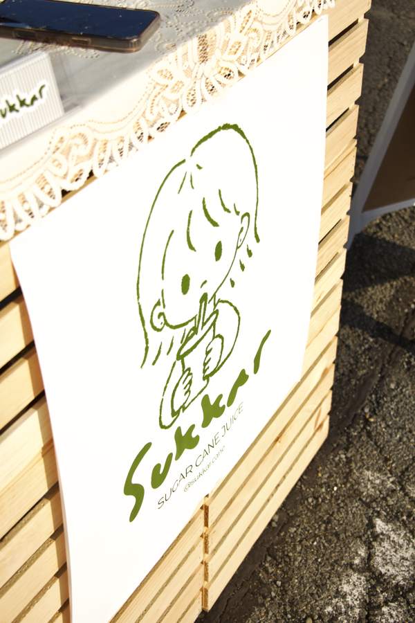 Sukkar logo poster hung on a wooden crate at a booth