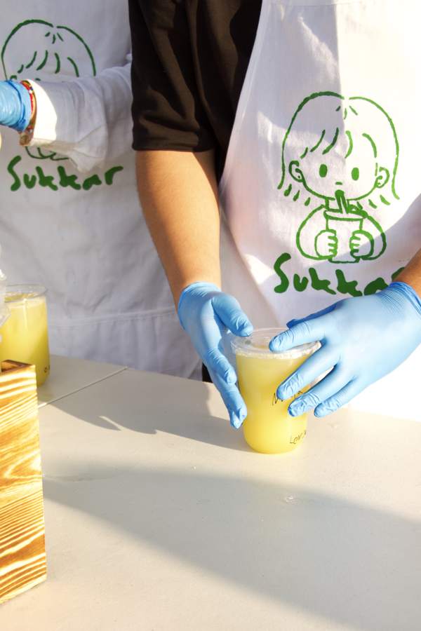 Two people in Sukkar aprons, one holding a cup